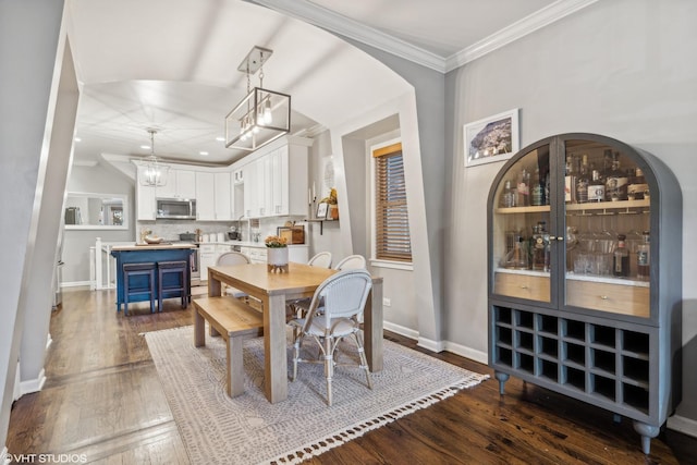 dining room with dark wood-type flooring, ornamental molding, and sink