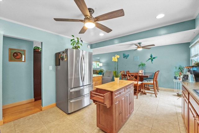 kitchen with a center island, ceiling fan, ornamental molding, light tile patterned flooring, and stainless steel refrigerator