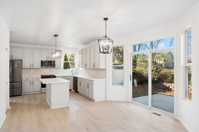 kitchen with pendant lighting, a center island, backsplash, sink, and appliances with stainless steel finishes