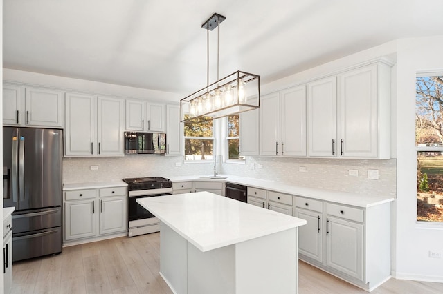 kitchen featuring sink, pendant lighting, decorative backsplash, a kitchen island, and appliances with stainless steel finishes