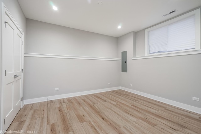 empty room featuring electric panel and light hardwood / wood-style flooring