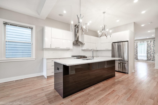 kitchen with white cabinetry, high end fridge, wall chimney exhaust hood, and sink