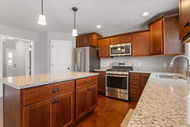 kitchen with pendant lighting, sink, a kitchen island, light stone counters, and stainless steel appliances