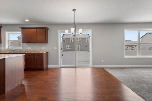 kitchen featuring light stone countertops, pendant lighting, plenty of natural light, and a notable chandelier