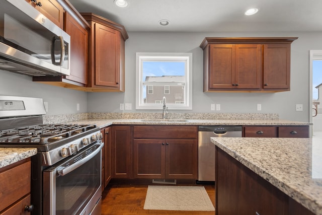 kitchen featuring dark hardwood / wood-style flooring, light stone counters, sink, and stainless steel appliances