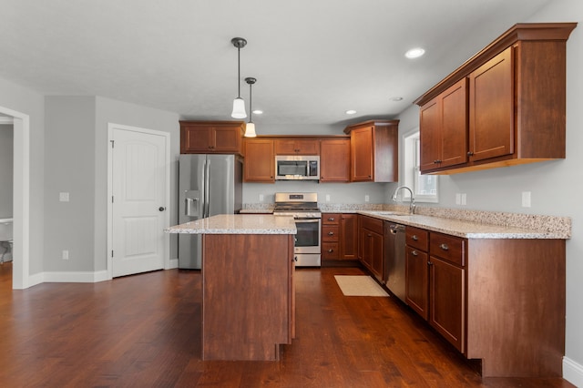 kitchen featuring sink, light stone countertops, appliances with stainless steel finishes, decorative light fixtures, and a kitchen island