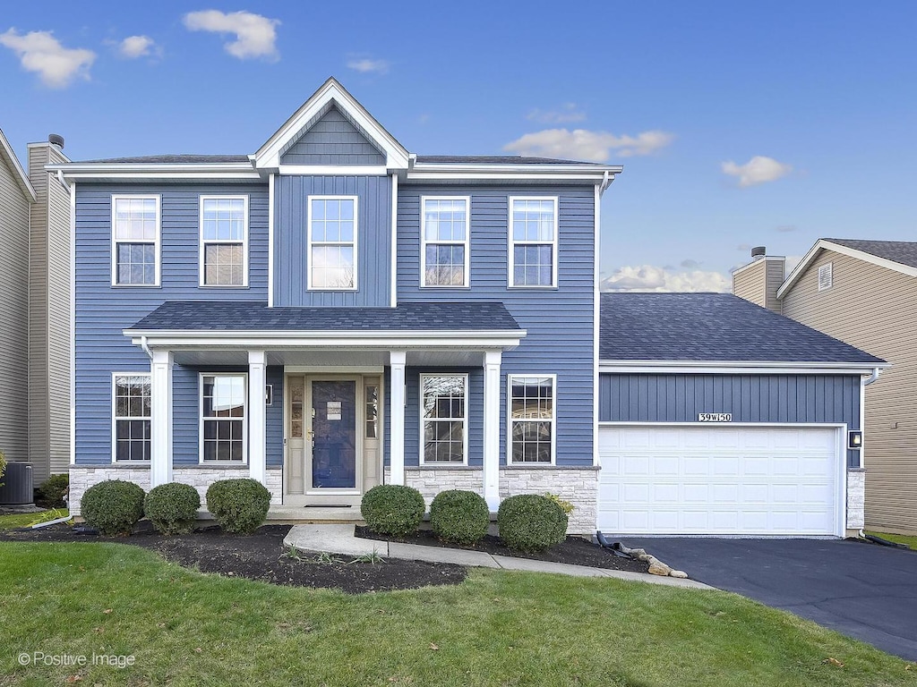 view of front facade with a front yard, central AC unit, and a garage