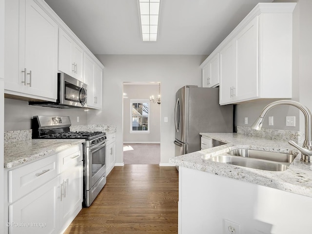 kitchen with light stone countertops, stainless steel appliances, dark wood-type flooring, sink, and white cabinetry