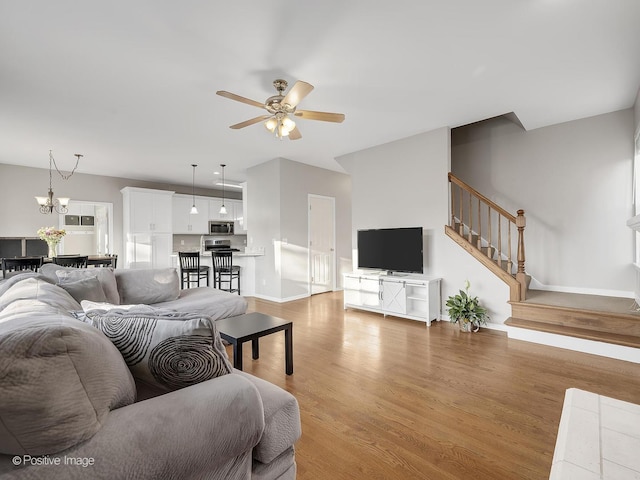 living room with ceiling fan with notable chandelier and light wood-type flooring