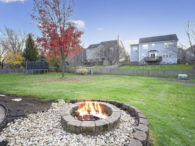 view of yard with a trampoline and a fire pit