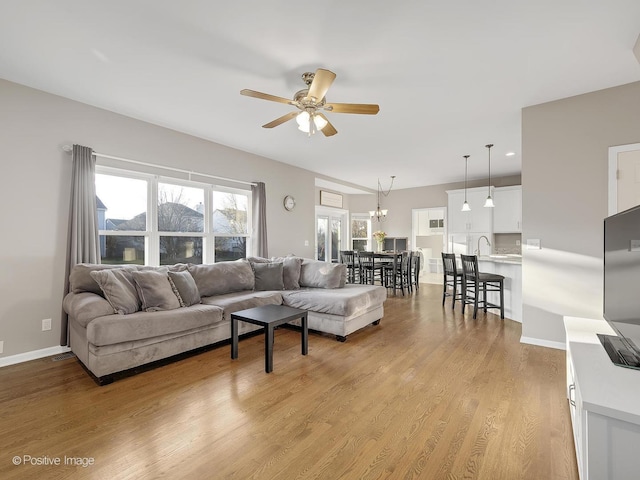 living room featuring light hardwood / wood-style floors, ceiling fan, and sink