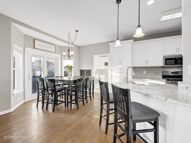 kitchen with light stone countertops, sink, a chandelier, white cabinets, and appliances with stainless steel finishes