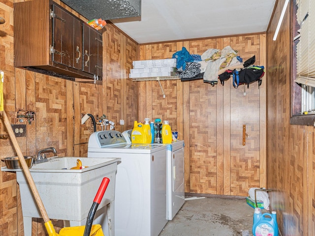 clothes washing area with cabinets, wood walls, washing machine and dryer, and sink