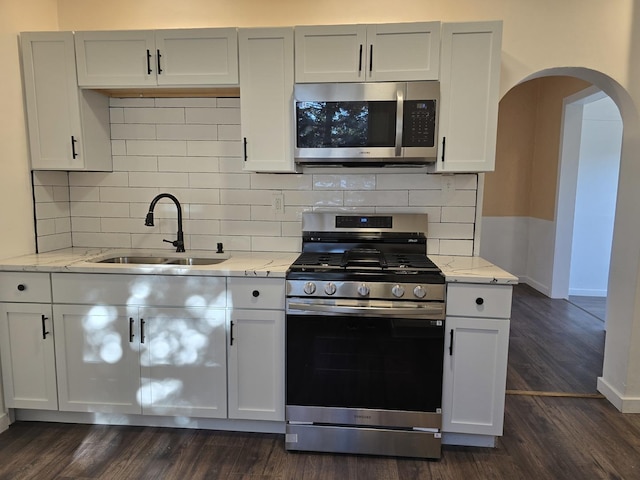 kitchen with sink, dark hardwood / wood-style flooring, light stone counters, white cabinetry, and stainless steel appliances