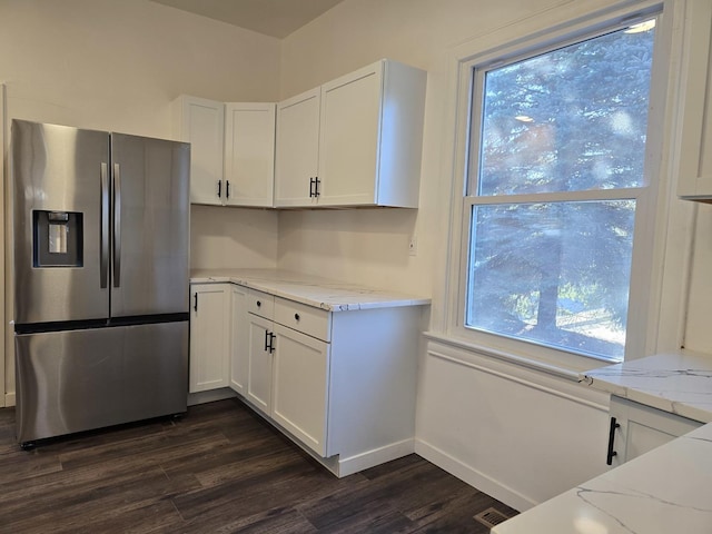 kitchen featuring stainless steel fridge with ice dispenser, white cabinetry, dark wood-type flooring, and light stone counters