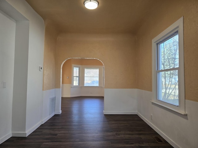 unfurnished room with a wealth of natural light and dark wood-type flooring