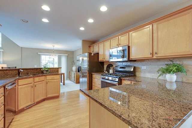 kitchen featuring decorative backsplash, appliances with stainless steel finishes, light brown cabinetry, sink, and decorative light fixtures