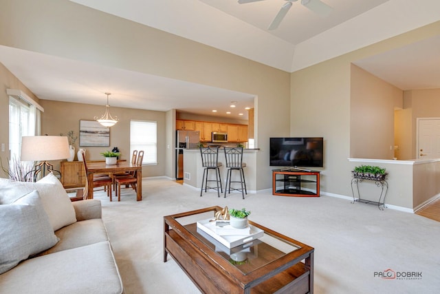 carpeted living room with ceiling fan, plenty of natural light, and lofted ceiling