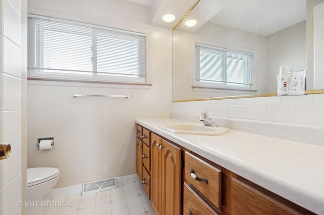 bathroom featuring toilet, vanity, tasteful backsplash, and tile patterned floors