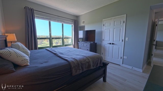 bedroom with a closet, light hardwood / wood-style flooring, and a textured ceiling