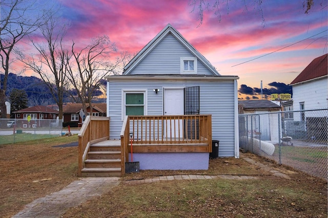 back house at dusk with a deck and a yard