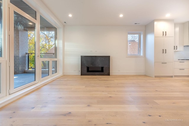 unfurnished living room with a high end fireplace and light hardwood / wood-style floors