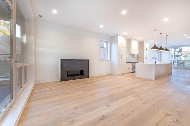 unfurnished living room featuring light wood-type flooring and sink