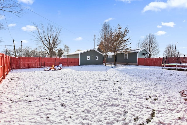 snow covered back of property with a trampoline