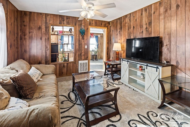 living room with ceiling fan, light carpet, and wood walls