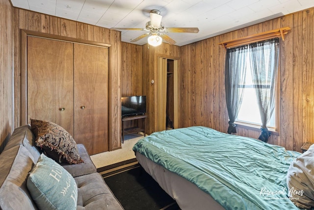 carpeted bedroom with ceiling fan and wooden walls