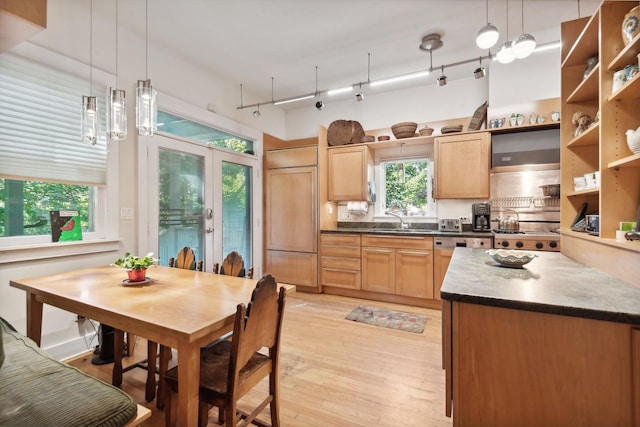 kitchen featuring paneled fridge, decorative light fixtures, light wood-type flooring, and sink