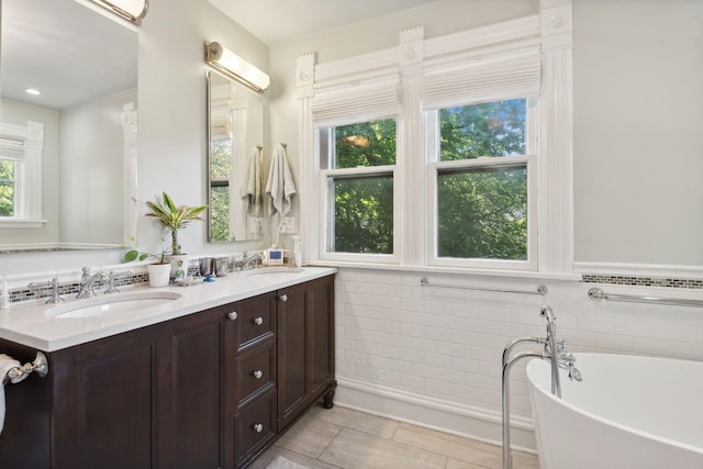 bathroom with a bathing tub, vanity, tile walls, and tile patterned flooring