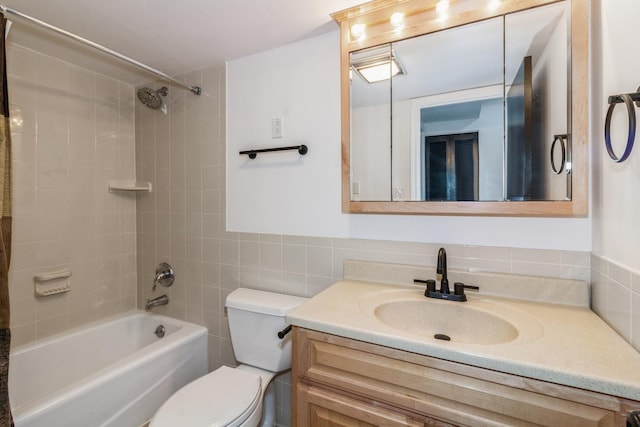 full bathroom featuring tiled shower / bath, vanity, toilet, and tile walls