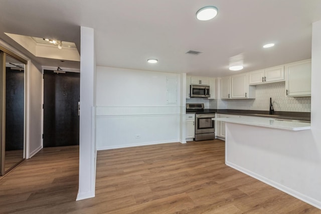 kitchen featuring white cabinets, sink, light hardwood / wood-style flooring, appliances with stainless steel finishes, and tasteful backsplash