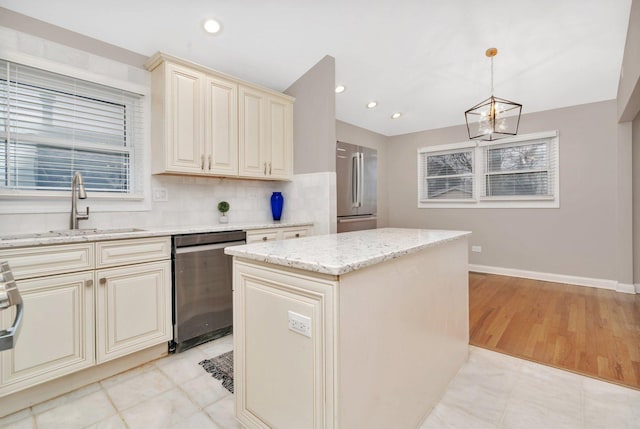 kitchen with appliances with stainless steel finishes, sink, hanging light fixtures, a center island, and cream cabinetry