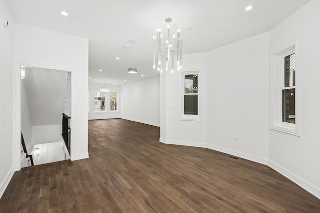 unfurnished living room featuring dark hardwood / wood-style flooring and a notable chandelier