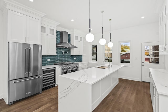 kitchen featuring wine cooler, wall chimney exhaust hood, high quality appliances, white cabinets, and sink