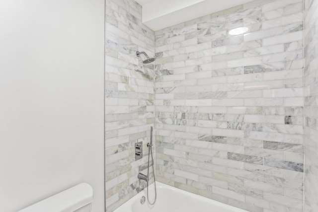 bathroom with toilet and tiled shower / bath