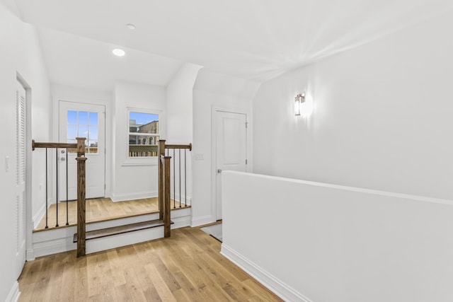 hallway featuring lofted ceiling and light hardwood / wood-style floors