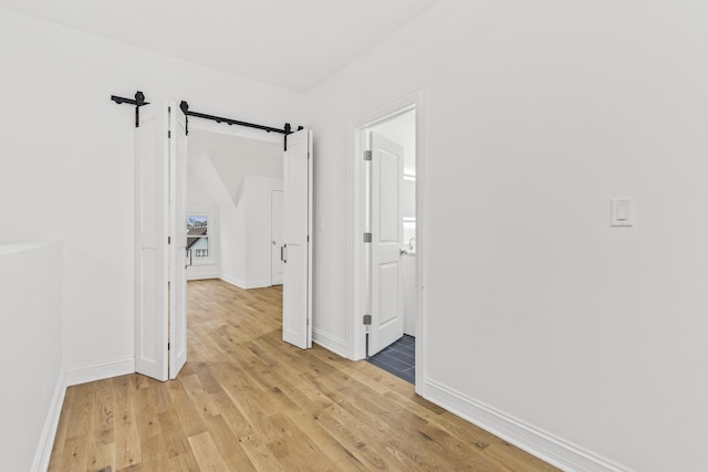 corridor with light hardwood / wood-style floors and a barn door