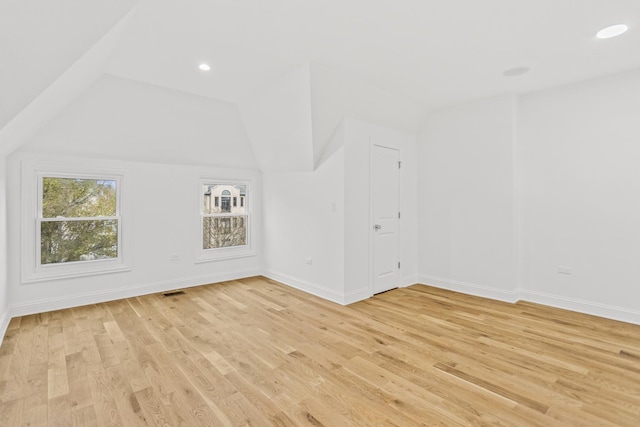 bonus room with light wood-type flooring and vaulted ceiling