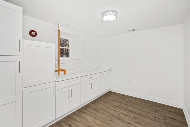 bar featuring dark wood-type flooring, white cabinets, and light stone countertops