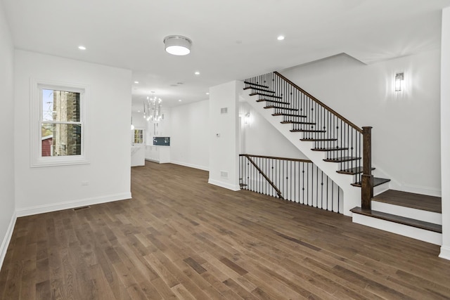 unfurnished living room featuring dark hardwood / wood-style flooring and a notable chandelier