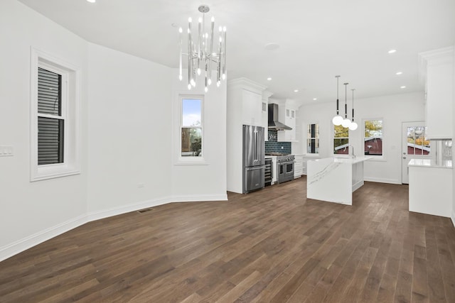 kitchen featuring premium appliances, white cabinets, a center island, wall chimney exhaust hood, and decorative light fixtures