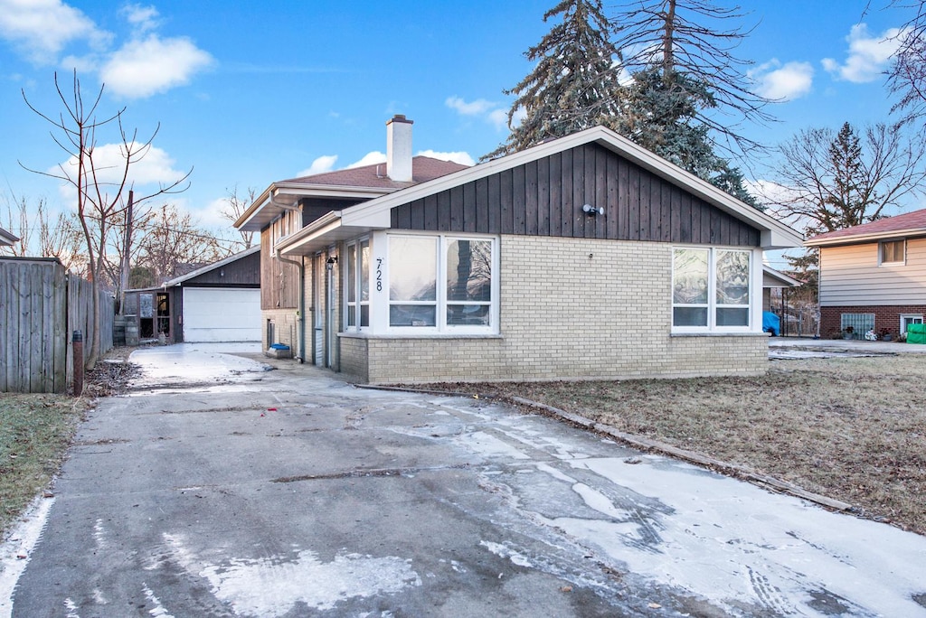 view of snowy exterior featuring a garage and an outbuilding