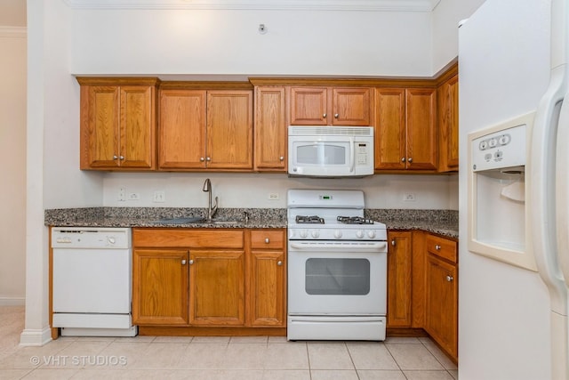 kitchen featuring white appliances, light tile patterned floors, sink, and dark stone countertops