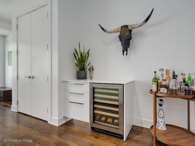 bar with wine cooler, dark wood-type flooring, and white cabinetry