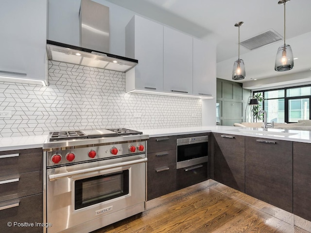 kitchen featuring white cabinetry, wall chimney range hood, appliances with stainless steel finishes, and decorative backsplash