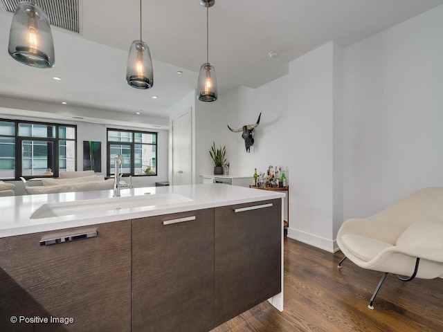 kitchen featuring sink, hanging light fixtures, dark hardwood / wood-style floors, and dark brown cabinets