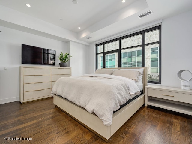 bedroom featuring dark hardwood / wood-style flooring and a tray ceiling